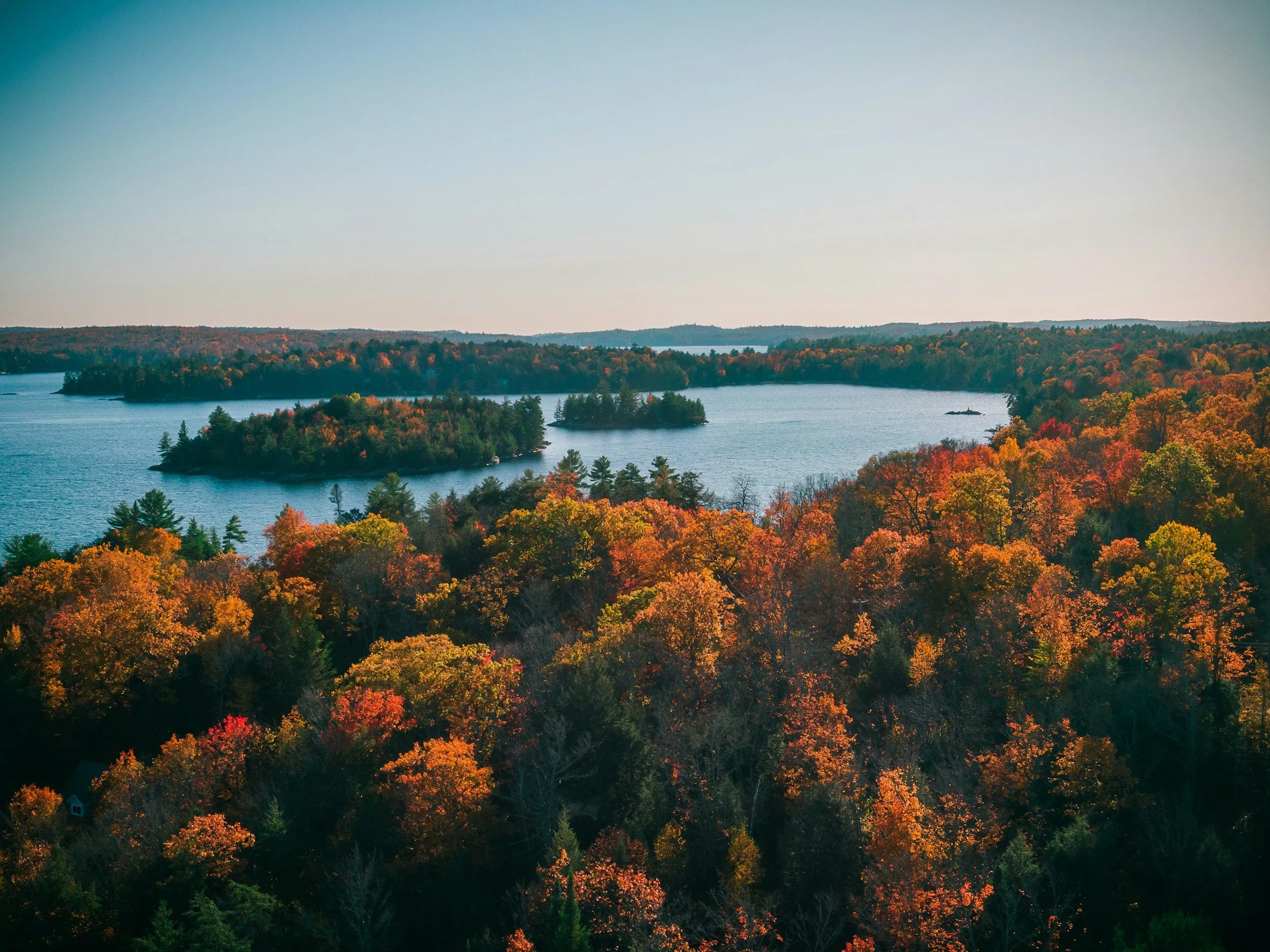 A lake ringed by autumn forest in the Near North, seen from above.